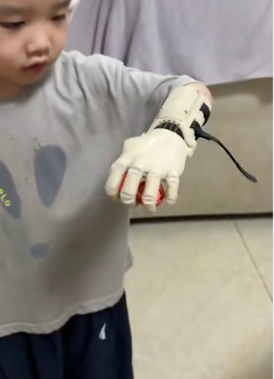 W.'s arm extended, fingers open, holding a red object