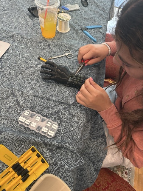 Laila threading tensioner cord through the finger joints