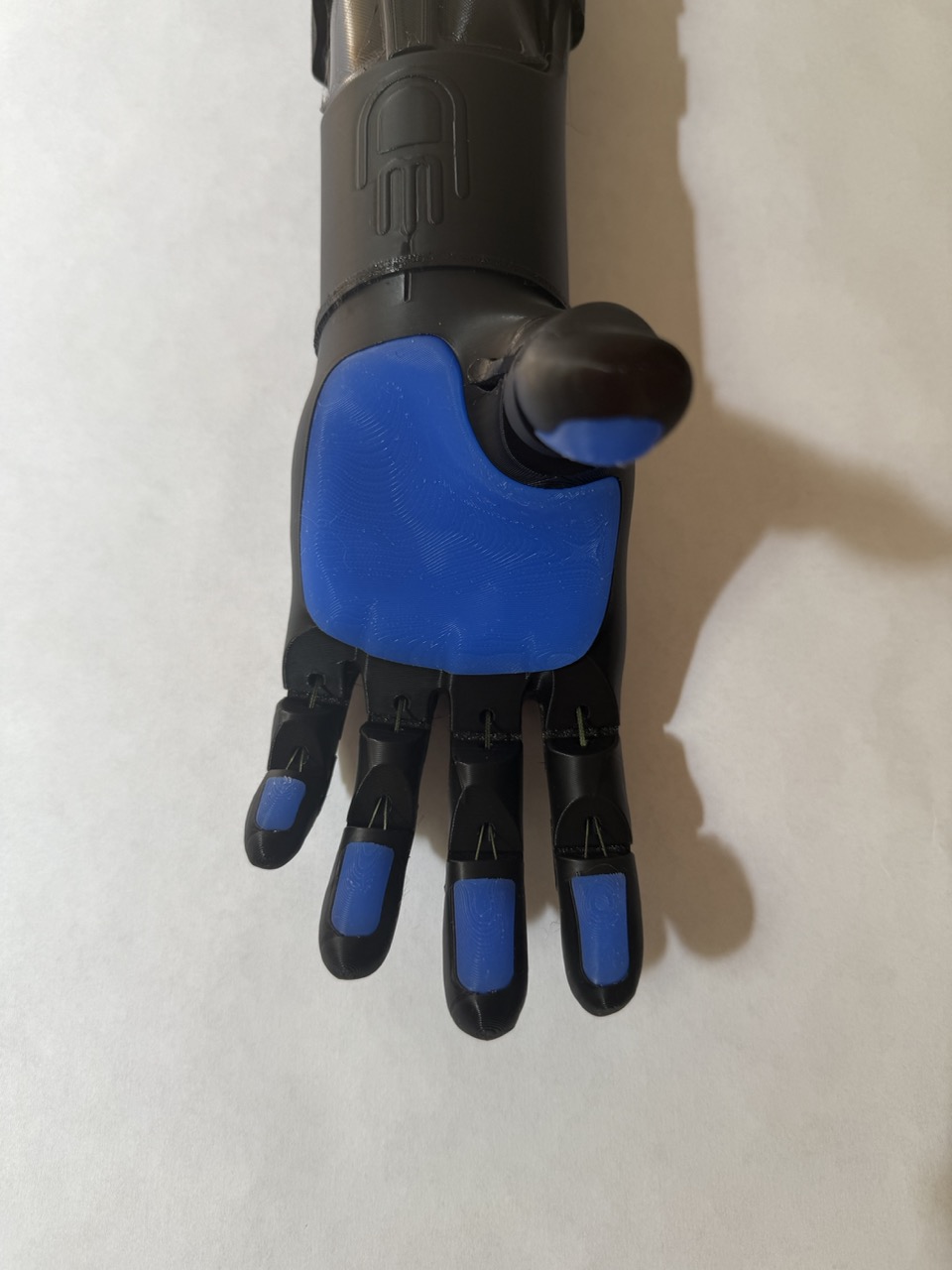 O.E.'s arm with fingers spread open showing palm and blue TPU grip pads