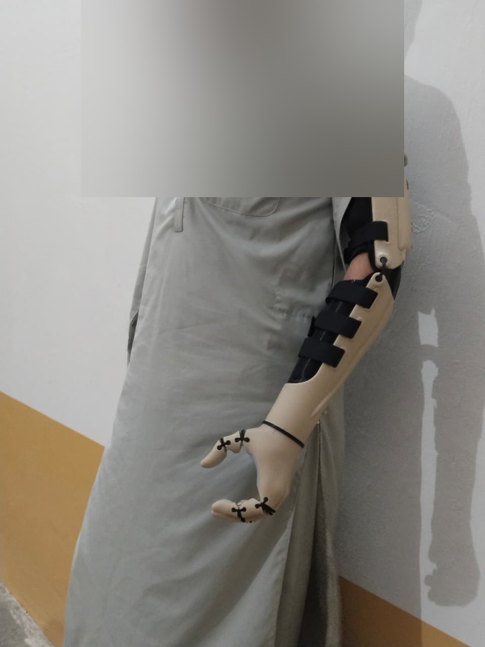A.S. standing in profile with the Kinetic Arm, fingers visible at side